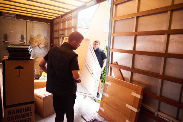 men moving furniture together into warehouse